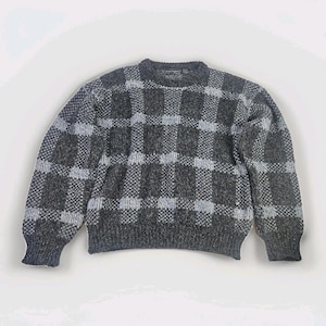 May include: A gray and charcoal plaid sweater with a crew neck and long sleeves. The sweater features a repeating checkered pattern. The cuffs and hem are ribbed. The sweater is made of a soft, textured material.