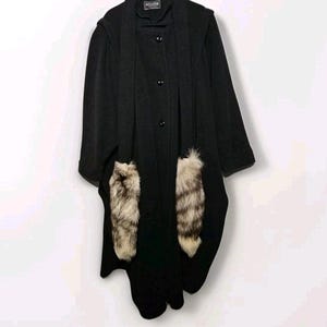 Puede incluir: Abrigo negro con capucha y ribete de piel en los bolsillos. El abrigo tiene cierre de botones y una etiqueta que dice "AGLIZION".