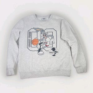 May include: A light gray sweatshirt featuring Bugs Bunny from Looney Tunes playing basketball. The graphic includes the number "00" and the words "Looney Tunes" and "World Champs".