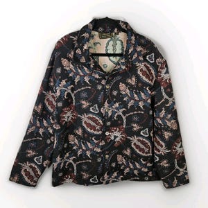 May include: A black button-down jacket with a paisley pattern in shades of red, blue, and pink. The jacket has a collared neckline and long sleeves. The interior lining is visible and features a floral design.