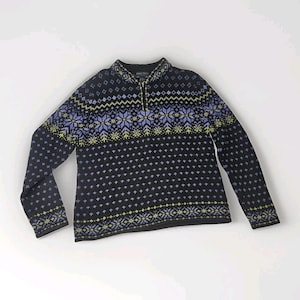 Könnte beinhalten: Ein schwarzer Pullover mit Reißverschluss und Muster. Der Pullover hat ein sich wiederholendes Muster aus kleinen weißen Punkten mit Bändern aus blauen, grünen und weißen geometrischen Formen auf Brust und Ärmeln. Der Pullover hat einen hohen Kragen.