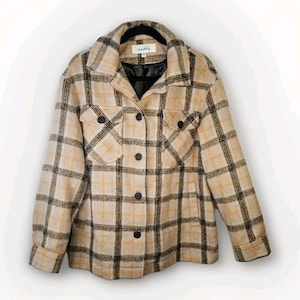 May include: A beige and black plaid jacket with a collared neckline, two chest pockets, and black buttons. The jacket is hanging on a black hanger. The brand name "scabby" is visible on the label.