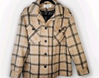 May include: A beige and black plaid jacket with a collared neckline, two chest pockets, and black buttons. The jacket is hanging on a black hanger. The brand name "scabby" is visible on the label.