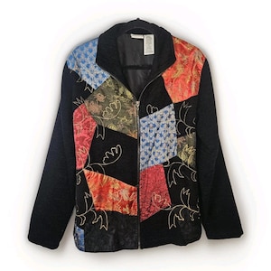 May include: Black zip-up jacket with patchwork design. The jacket features a black quilted body with colorful patchwork panels in red, blue, and gold. The patchwork has floral and paisley patterns. The jacket has a black collar and sleeves.