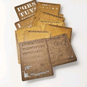 May include: A selection of vintage lettering guides and stencils in various sizes and shapes. The guides are made of a tan-coloured material with printed text and cut-out letters and numbers. Some guides feature maps of the United States.