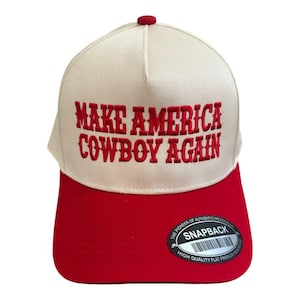 以下が含まれることがあります： 「MAKE AMERICA COWBOY AGAIN」の刺繍が施された、赤とクリーム色のスナップバックハット。 赤いツバとクリーム色のクラウンが特徴です。 上部には小さな赤いボタンが付いています。 ハットには「SNAPBACK」ステッカーが付いています。