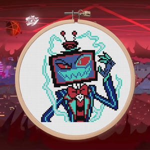 Op de afbeelding: Kruissteekborduurwerk in een houten hoepel. Het ontwerp toont een robotpersonage met een tv-schermhoofd, een vlinderdas en een blauwgroen en blauw kleurenschema. De achtergrond is een rood en paars stadsbeeld.