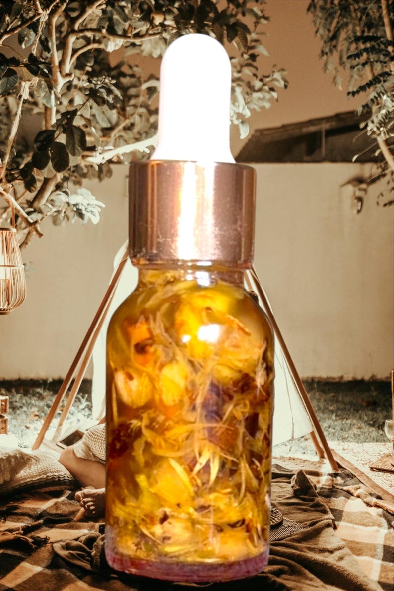 Puede incluir: Una botella de vidrio transparente con tapa dorada y gotero. La botella est&aacute; llena de un l&iacute;quido amarillo y contiene flores amarillas secas.