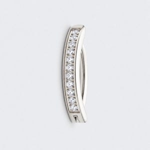 May include: A curved silver-toned navel piercing bar featuring a vertical channel setting of ten clear, round-cut stones. The metal has a polished, reflective finish, and the piece is designed with a smooth, solid bar on the inner curve.