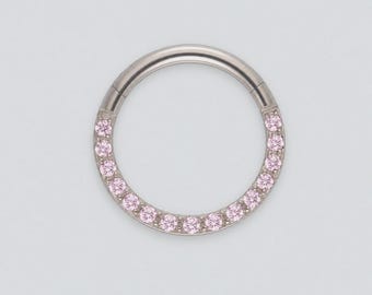 May include: A circular hinged hoop ring made of polished silver-toned metal. The lower portion of the hoop is set with a row of small, round, light pink gemstones that are evenly spaced along the front-facing surface of the jewelry piece.