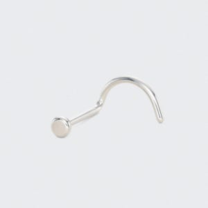 May include: A silver nose stud with a curved post and a small, flat, circular end. The jewellery is designed for a nose piercing and is shown against a white background.