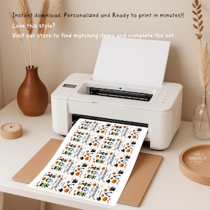 May include: A white printer outputting a sheet of paper featuring twelve rectangular Halloween-themed gift tags. Each tag displays colorful illustrations of ghosts, pumpkins, and monsters with the text Happy Halloween printed on each label.