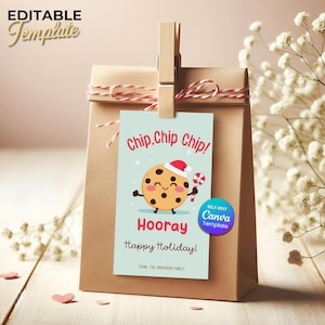 May include: A brown paper gift bag with a red and white string tied around the top. A light blue tag is clipped to the bag with a wooden clip. The tag reads "Chip, Chip, Chip!" and features a cartoon cookie with a Santa hat and candy cane. The tag also says "Hooray" and "Happy Holiday!"