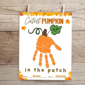 Puede incluir: Una impresión rectangular blanca con una huella de mano naranja en forma de calabaza, una hoja verde y un tallo marrón. El texto dice Cutest PUMPKIN in the patch, Name: Emma y Date: 18/08/2026. El borde está decorado con hojas de otoño.