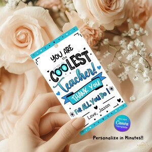 May include: A white gift tag with a blue border and the text "YOU ARE the COOLEST Teacher! THANK YOU FOR ALL YOU DO!" in a handwritten style. The tag includes the text "Love, Jason" and is decorated with hearts and stars.