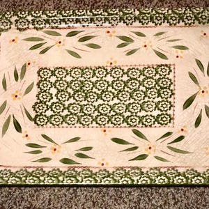 May include: Rectangular ceramic serving tray with a cream-colored surface and green floral and leaf patterns. The tray has green handles and a decorative border. The center features a repeating floral design.