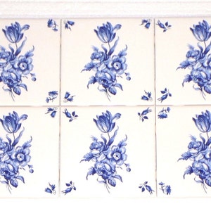 May include: Six white ceramic tiles with a blue floral design. Each tile features a central bouquet of flowers and a tulip, with smaller floral accents in the corners. The design is in shades of blue.