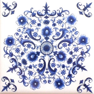 May include: Square white ceramic tile with a detailed blue floral design. The pattern features stylized flowers, leaves, and swirling vines arranged in a symmetrical composition. Decorative elements include small star-shaped flowers and ornate flourishes.
