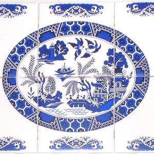 May include: A set of six white ceramic tiles with a blue and white Willow pattern design. The central oval design depicts a landscape with a pagoda, boat, and birds. Decorative blue borders frame the tiles.