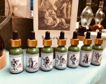 May include: Seven small green glass bottles with gold caps and labels. Each bottle has a different image of a person in a historical costume. The labels read "Alchemical Savaric Elixir" and "Ens" with a small red symbol.