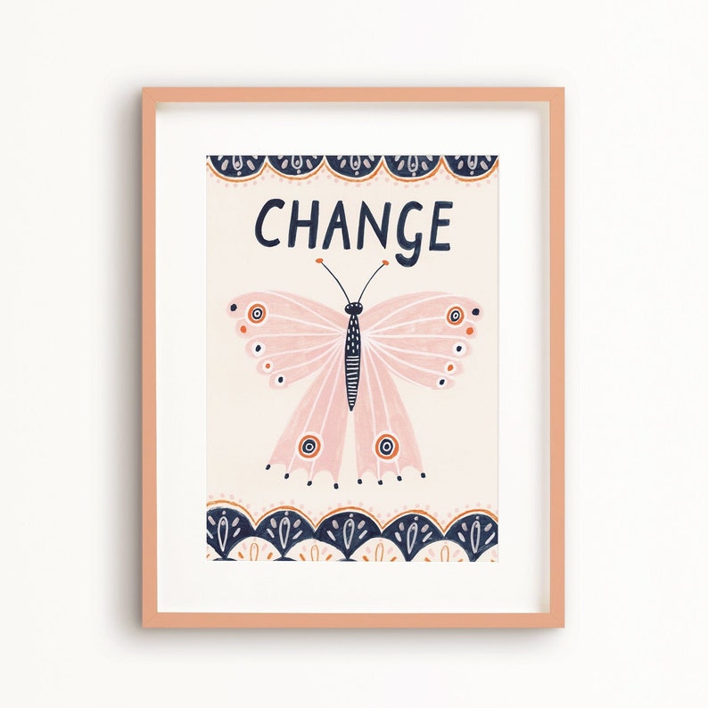 May include: A framed art print featuring a pink butterfly illustration with the word "CHANGE" in navy blue. The butterfly has orange and navy accents. The print is framed in a light peach-colored frame.