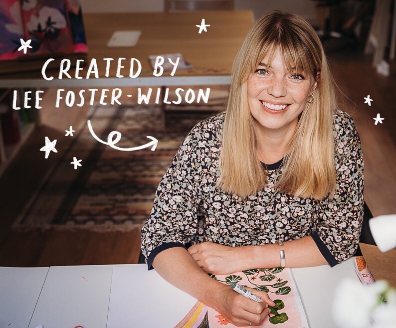 May include: A smiling person with blonde hair and a floral print top is seated at a table. The text "CREATED BY LEE FOSTER-WILSON" is above the person. The person is holding a pen and drawing on a piece of paper. White stars are scattered around the text.
