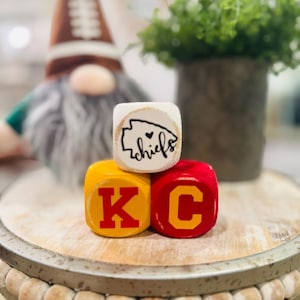 May include: Wooden blocks spelling "KC" in red letters on yellow blocks, with a white block on top that says "chiefs" with a heart symbol.