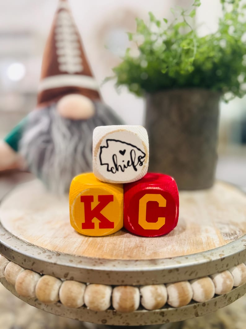 May include: Wooden blocks spelling "KC" in red letters on yellow blocks, with a white block on top that says "chiefs" with a heart symbol.
