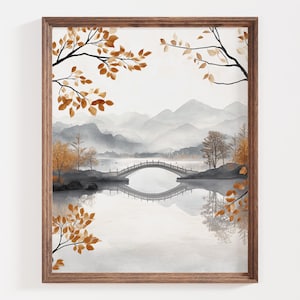 May include: Watercolor painting of a serene landscape with a bridge over a lake, framed in a wooden frame. The artwork features a muted color palette of grays, browns, and oranges, with mountains in the background and autumn foliage.