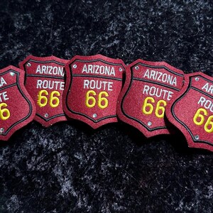 May include: Five red felt patches with white stitching and gold lettering. Each patch reads "Arizona Route 66".