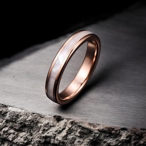 Peut inclure: Une alliance en or rose avec une incrustation de nacre blanche.