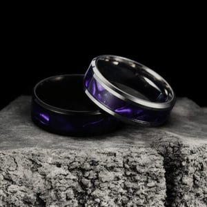 May include: Two silver rings with a purple inlay. The rings are stacked on top of each other.