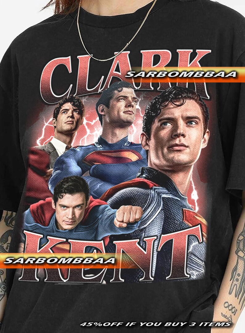 May include: Black t-shirt featuring a graphic of Clark Kent in various poses, with the text "CLARK KENT" in red. The shirt has a vintage look, with a faded design and the text "SARBOMBBAA".