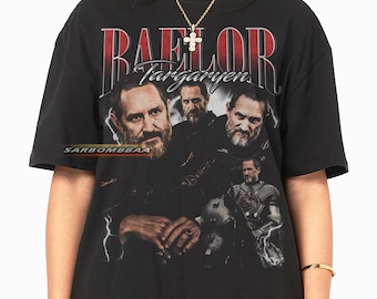 May include: Black t-shirt featuring a graphic of a man with the text "BAELOR Targaryen" in red and white. The design includes multiple images of the man in various poses. The shirt has a crew neck and short sleeves.