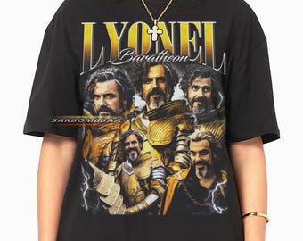 May include: Black t-shirt featuring a graphic of a man in golden armor with the name "LYONEL Baratheon" in gold lettering. The design includes multiple images of the same man. The shirt has a crew neck and short sleeves.