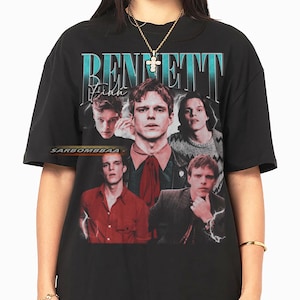 Könnte beinhalten: Schwarzes T-Shirt mit einem Vintage-Grafikdesign, das einen Mann mit dem Namen "BENNETT" in Türkis zeigt. Das Design enthält mehrere Bilder des Mannes und den Text "Finn" in einer Schriftart. Das Shirt hat auch den Text "SARBOMBBAA" unten.