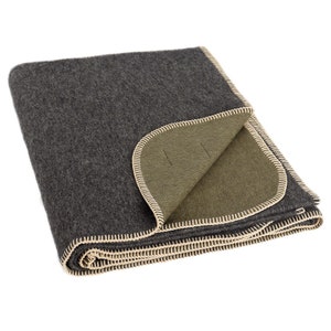 May include: A grey and green wool blanket with a cream coloured stitched border. The blanket is folded in half and the green side is visible.
