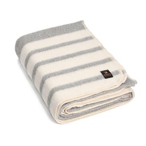 May include: A white and gray striped alpaca wool throw blanket with a brown label that says "Alpaca Warehouse".