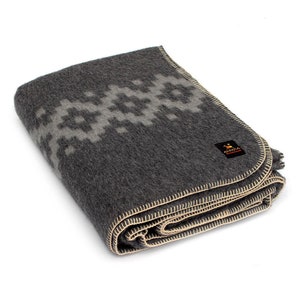 May include: A gray wool blanket with a white geometric pattern and a tan border. The blanket is folded in half and has a small label that says "Alpaca" on it.