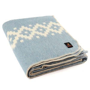 May include: A light blue wool blanket with a white geometric pattern. The blanket is folded and has a cream-colored border.