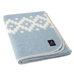 Peut inclure: Une couverture en laine d'alpaga bleu clair avec un motif géométrique blanc. La couverture est pliée et a une bordure blanche. La couverture porte une étiquette indiquant "Alpaca Warehouse".