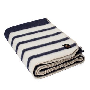 May include: A folded white and navy blue striped wool blanket with a small brown label that says "Eskimo" on it.