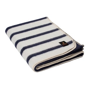 May include: A white and navy blue striped alpaca wool throw blanket with a cream colored border and a small "Alpaca" brand label.