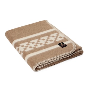 Peut inclure: Une couverture en laine d'alpaga marron avec un motif géométrique blanc et une petite étiquette marron sur laquelle est inscrit "Alpaca" en lettres blanches.