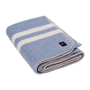 May include: A blue wool blanket with two white stripes. The blanket is folded and has a white stitched border.