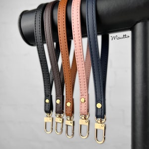 Photo of petite leather wrist strap key chain accessories, in black, dark brown, dark tan patina, pink blush and navy leather colors.