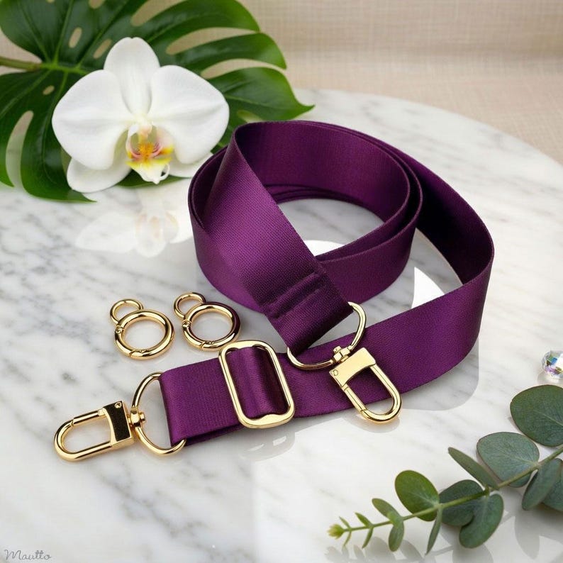 Photo of neverfull tote crossbody strap conversion kit contents in purple colorway, displayed on a marble surface with flowers/leaves.