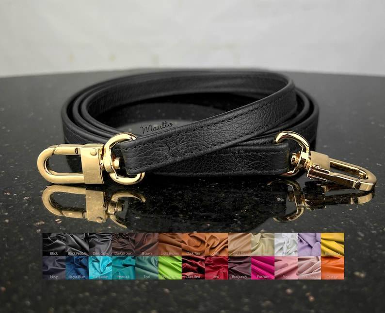 May include: Black leather purse strap with gold-colored metal clasps. The strap is rolled up, showing its length and texture. A color palette of leather swatches is displayed below the strap.