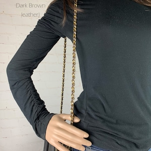 Photo of mannequin with long shoulder strap on handbag.