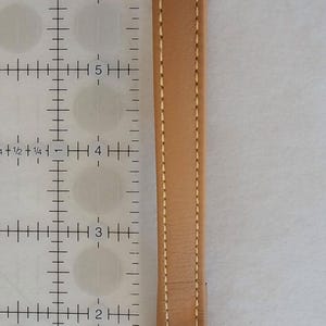 Leather wrist strap next to inches ruler.